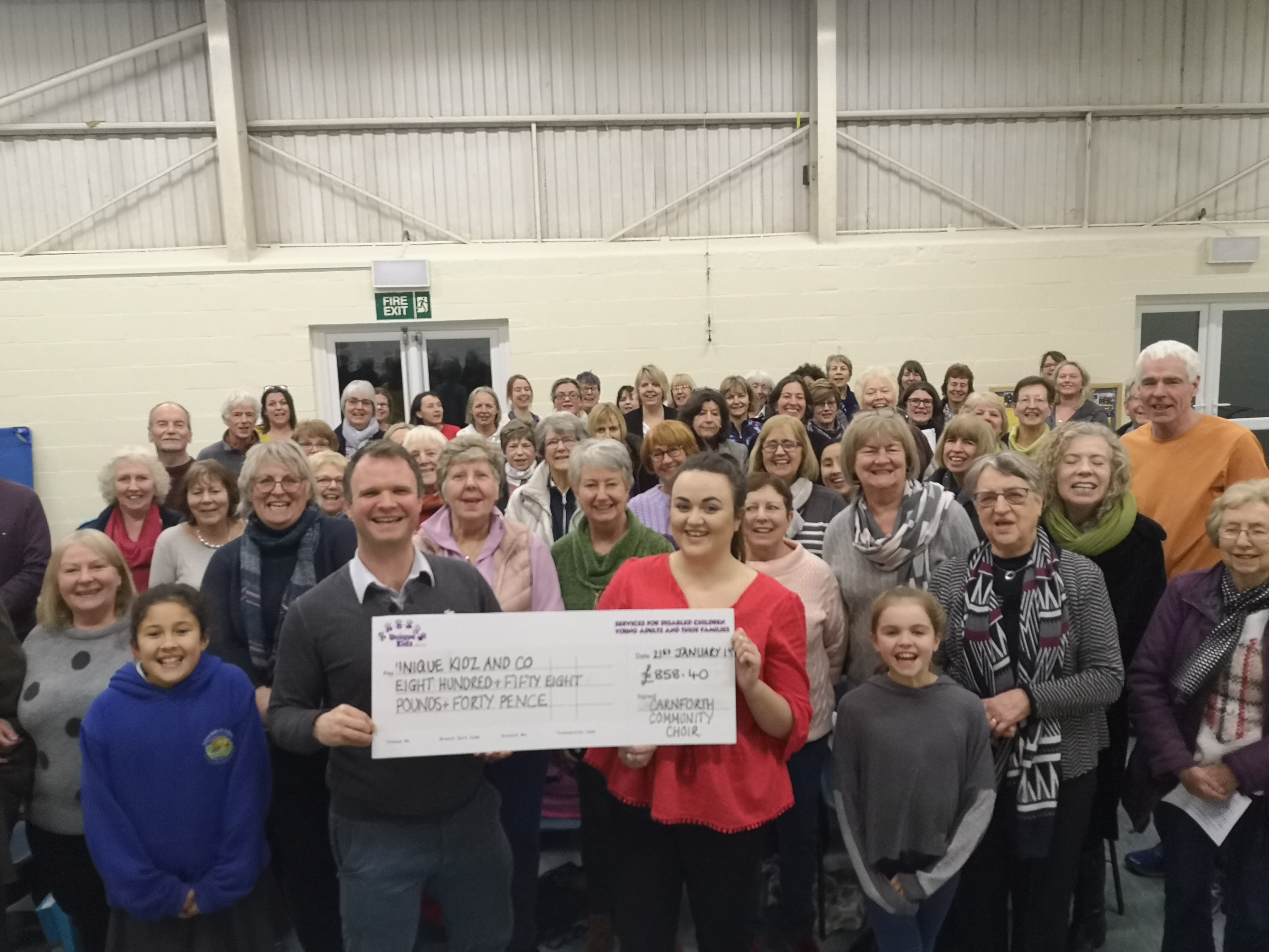 Carnforth Community Choir presenting Unique Kidz and Co with a cheque